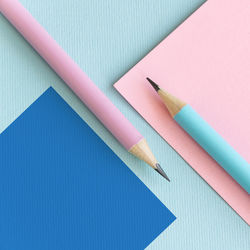 High angle view of pencils with paper on colored background