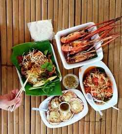 Cropped image of person holding chopsticks against meal on table