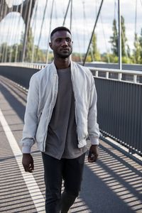 Portrait of young man standing on footbridge