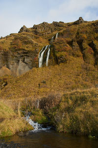 Stream flowing through rocks against sky