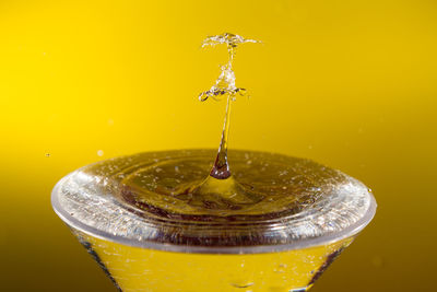 Close-up of water drops on glass against yellow background