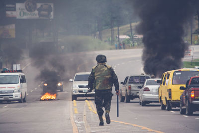 Rear view of soldier walking on street in city