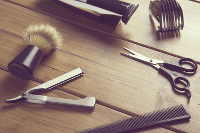 High angle view of scissors and comb with razor on table