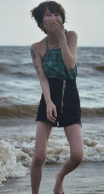 Full length of woman standing at beach against sky