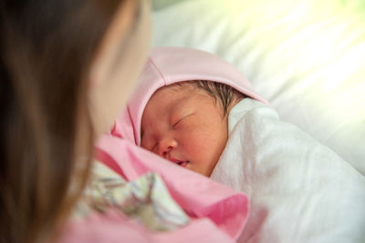 Mother holding cute baby on bed