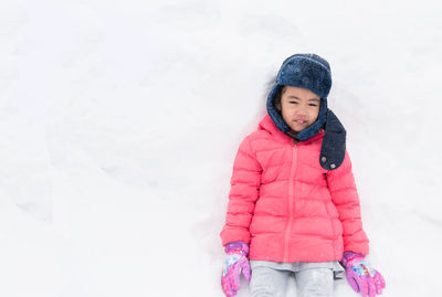Full length of a smiling girl standing in snow