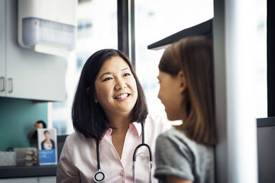 Smiling female doctor measuring girl's height in clinic