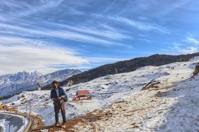 Man standing on mountain against sky during winter