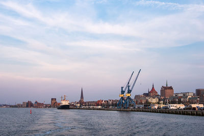 View of buildings by sea against cloudy sky