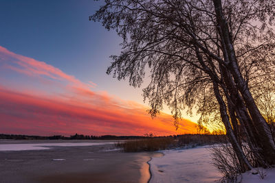 Scenic view of lake against orange sky during winter