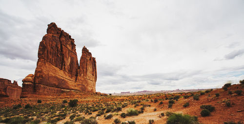 Rock formations on landscape against cloudy sky