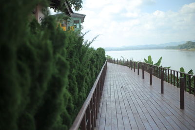 Walkway by sea against sky