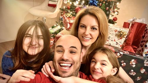 Portrait of l family with christmas tree at home