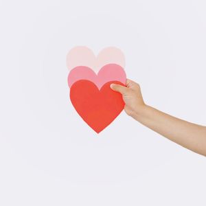 Close-up of woman holding heart shape over white background