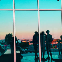 People looking at city seen through glass window