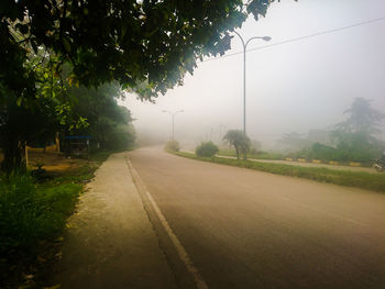 Road by trees against sky