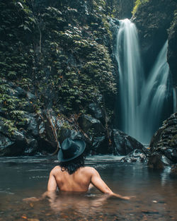 Rear view of shirtless man in water