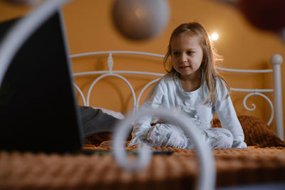 Child watching cartoons on laptop. serious kid with technology at home on bed spending time on-line