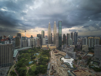 High angle view of modern buildings in city against cloudy sky