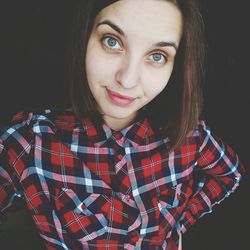 Portrait of smiling young woman against black background