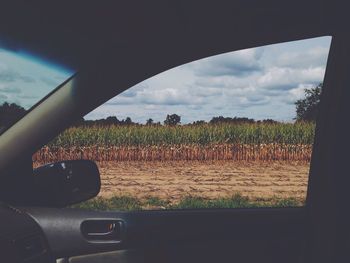 View of field against cloudy sky