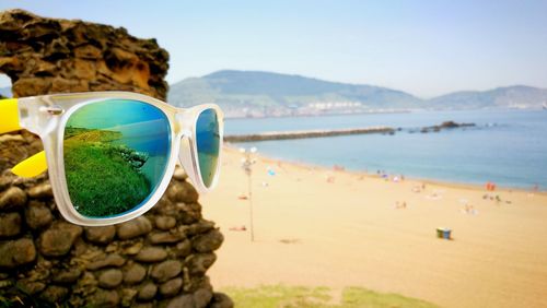 Close-up of sunglasses on beach against clear sky