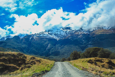 Road amidst snowcapped mountains against sky