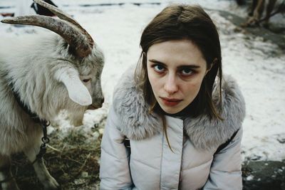 Portrait of young woman with goat in winter
