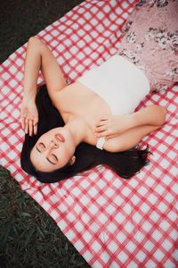 High angle view of woman lying on picnic carpet