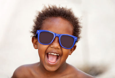 Close-up portrait of boy with mouth open wearing sunglasses