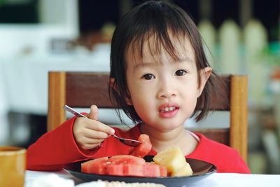 Close-up portrait of cute girl eating food at home