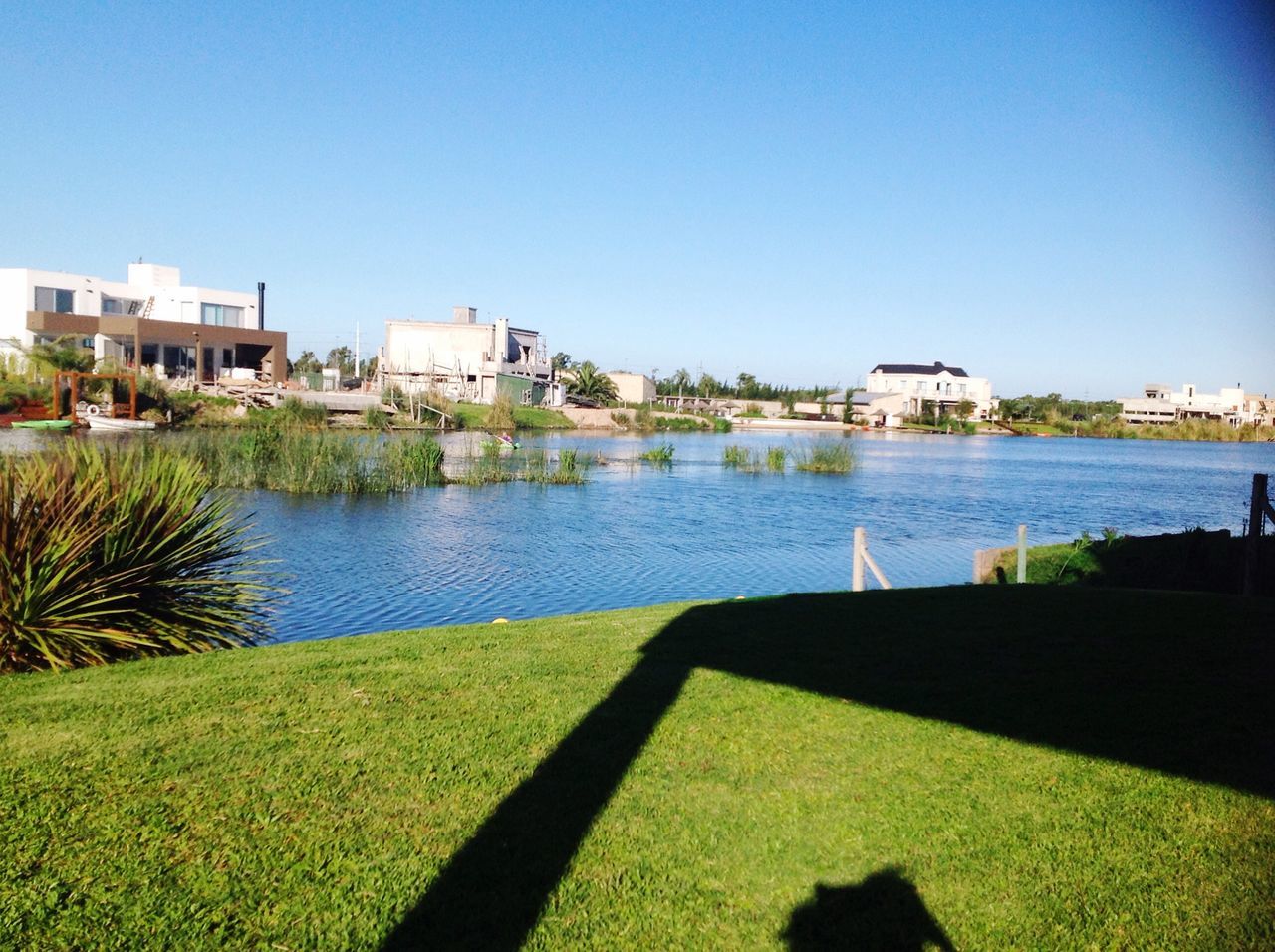 blue, building exterior, clear sky, architecture, built structure, water, sunlight, sky, day, outdoors, no people, tree, grass, city, nature