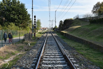 Railroad tracks by trees against sky