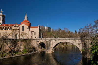 Arch bridge over river against clear blue sky