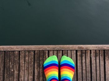 Close-up of person wearing colorful sock on pier over lake