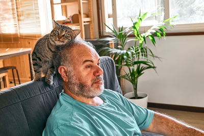 Tabby cat licking face of bearded man in living room. human-animal relationships. pets care.