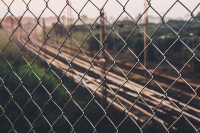 Railroad tracks seen through chainlink fence