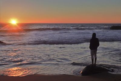 Rear view of man looking at sea during sunset