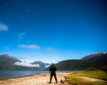 Rear view of man standing on mountain against sky