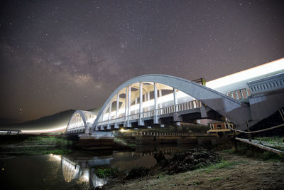 Arch bridge over river against sky at night