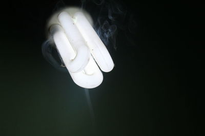 Low angle view of illuminated light bulb against black background