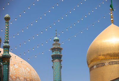 Low angle view of string lights hanging on mosque against sky during sunny day