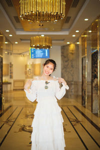 Portrait of smiling woman standing in corridor