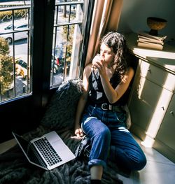 Woman using phone while sitting on seat at home