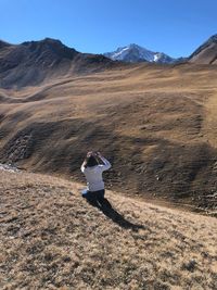 Rear view of woman taking photograph of mountains