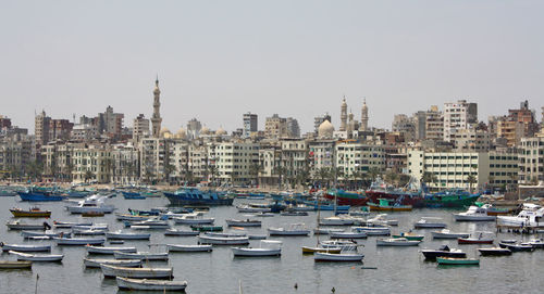 Sailboats in city against clear sky
