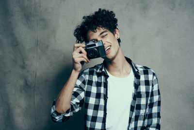 Portrait of man photographing against wall