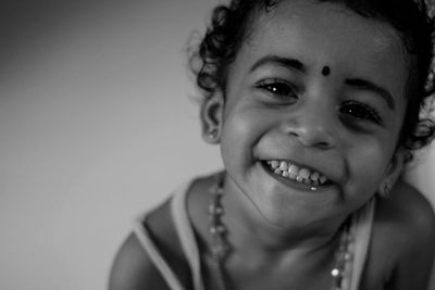 Close-up portrait of smiling girl against wall