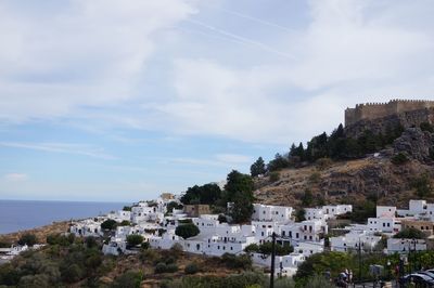 Buildings by sea against sky