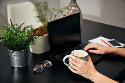 Midsection of man holding coffee cup on table